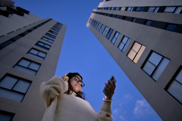 Photo une jeune femme regarde son téléphone portable tout en écoutant de la musique vue d'en bas la nuit