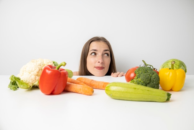 Une jeune femme regarde sous la table où se trouvent les légumes frais