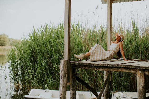 Jeune femme relaxante sur une jetée en bois au bord du lac calme