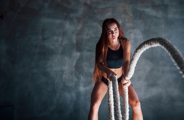 Jeune femme de remise en forme avec un corps mince faisant des exercices avec des nœuds dans les mains.