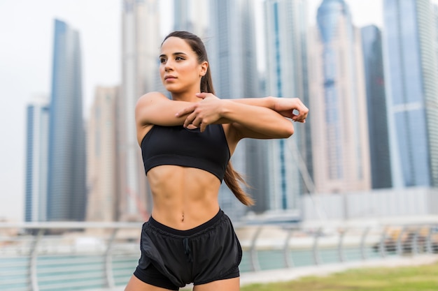 Jeune femme de remise en forme faire des exercices de réchauffement des mains avant de courir contre l'espace des gratte-ciel