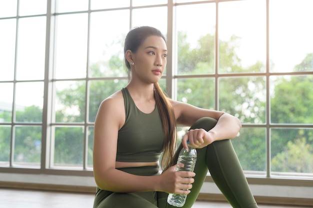 Jeune femme de remise en forme en tenue de sport buvant de l'eau après avoir fait de l'exercice à la maison