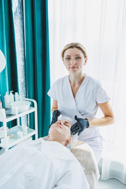 Une jeune femme à un rendez-vous avec une esthéticienne Une cosmétologue donne un massage du visage à sa cliente Facial Un voyage chez l'esthéticienne