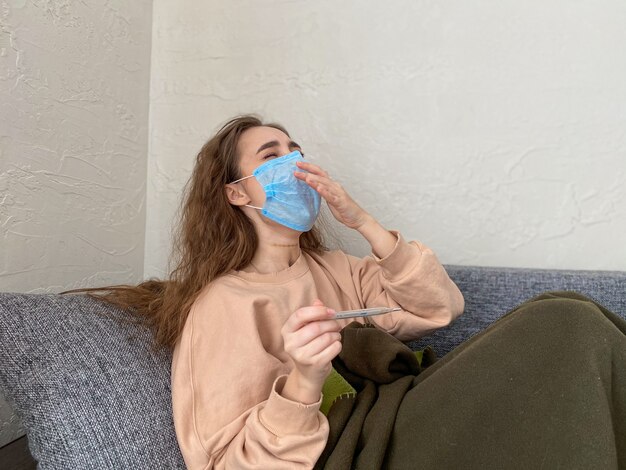 La jeune femme reste isolée à la maison avec des signes d'infection virale. Une femme en ambulatoire. concept de quarantaine à domicile, coronavirus