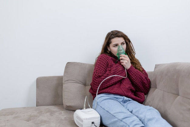 Photo jeune femme reste à la maison assise sur le canapé, malade