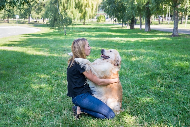 Jeune femme et retriever sur fond d'herbe verte à l'air frais.