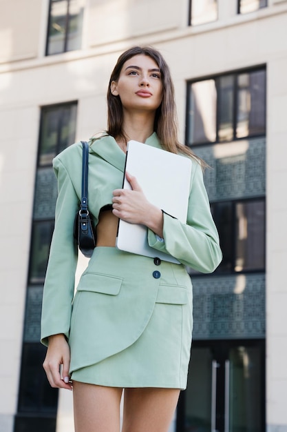 Une jeune femme réussie avec un ordinateur portable pose à l'extérieur