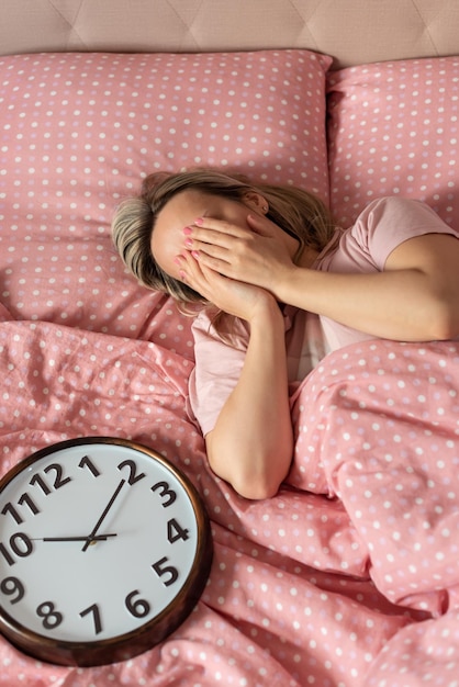 Jeune femme avec réveil sur le lit le matin Se réveiller sur un réveil Bonjour Sommeil sain L'horloge biologique Rythmes circadiens