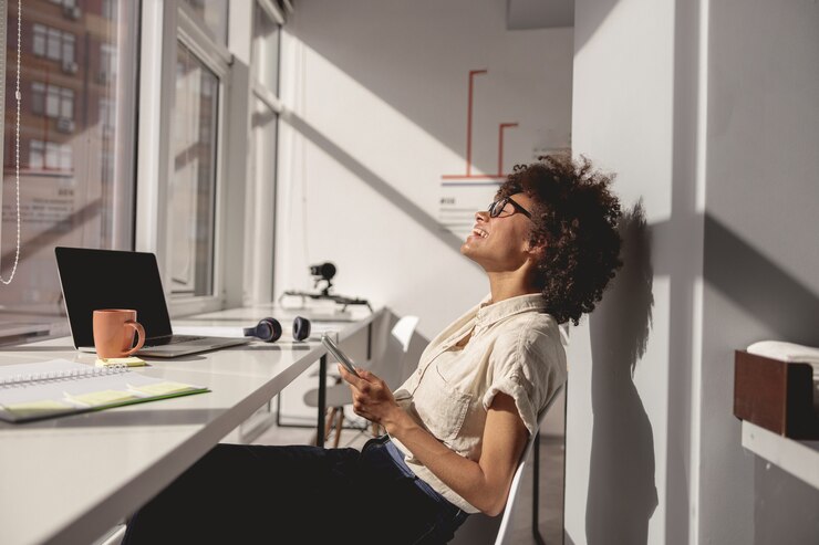 Photo jeune femme riant assise sur une chaise au bureau