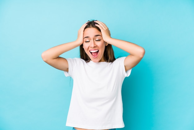 Jeune femme rit joyeusement en gardant les mains sur la tête