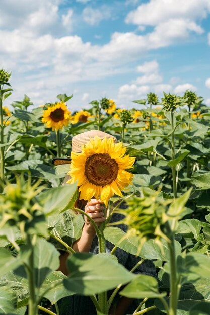 Jeune femme rit avec tournesol sur son visage portrait sans visage de jeune femme au chapeau de paille avec