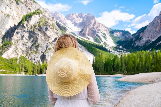 Une jeune femme en robe blanche et chapeau appréciant le pittoresque lac Braies et les Dolomites Alpes Italie