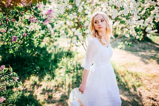 Jeune femme en robe blanche dans un jardin fleuri