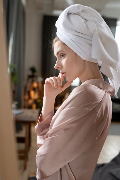 Jeune femme en robe de chambre faisant la préparation du matin à la maison