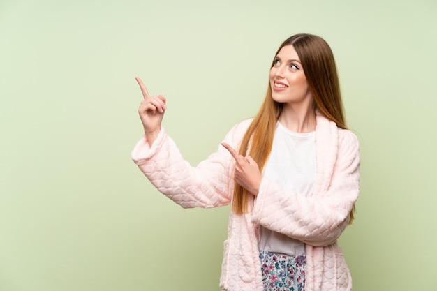 Jeune femme en robe de chambre pointant avec l'index une excellente idée