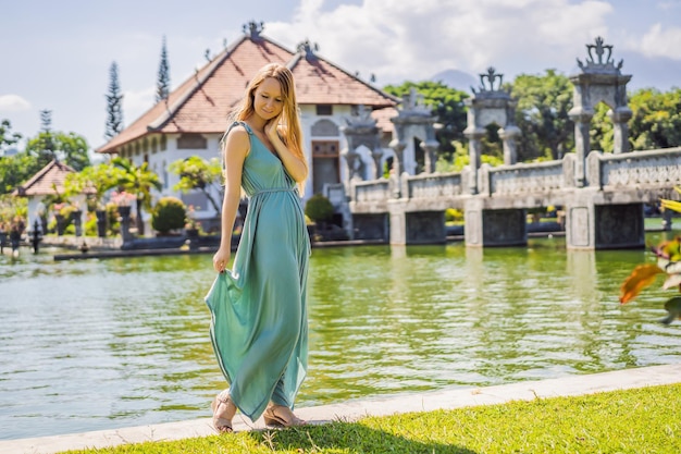 Photo jeune femme en robe dans le palais de l'eau soekasada taman ujung ruines sur l'île de bali en indonésie incroyable architecture ancienne voyage et vacances fond