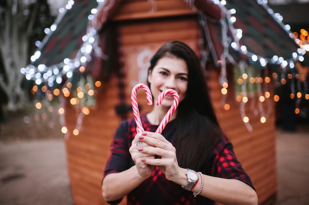 Jeune femme en robe debout près de la maison décorée pour Noël