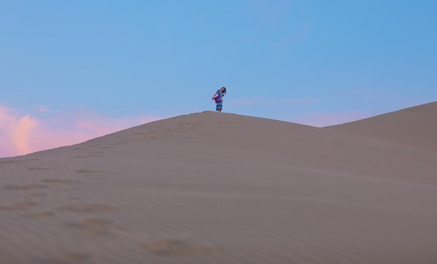 Jeune femme en robe d'été marchant sur les dunes du désert