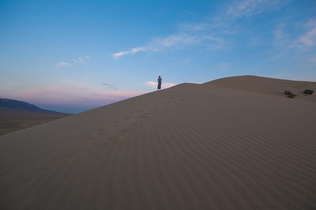 Jeune femme en robe d'été marchant sur les dunes du désert