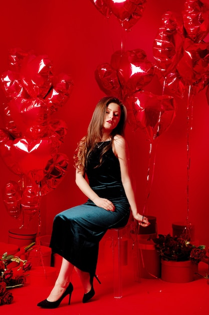 Jeune femme en robe longue avec des ballons rouges en forme de coeur