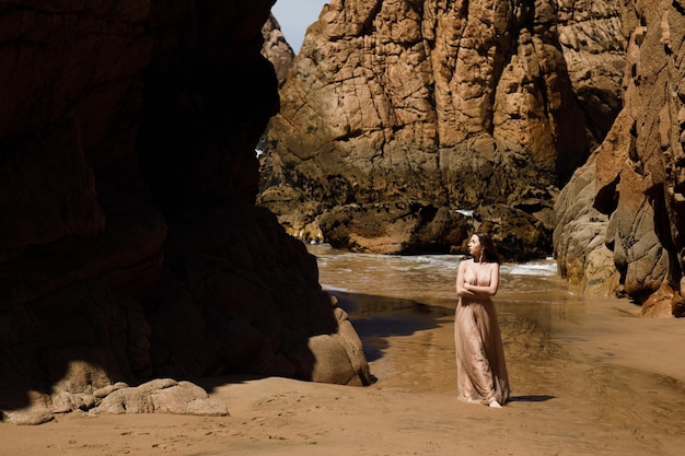 jeune femme en robe longue marchant sur la plage près de l'océan.