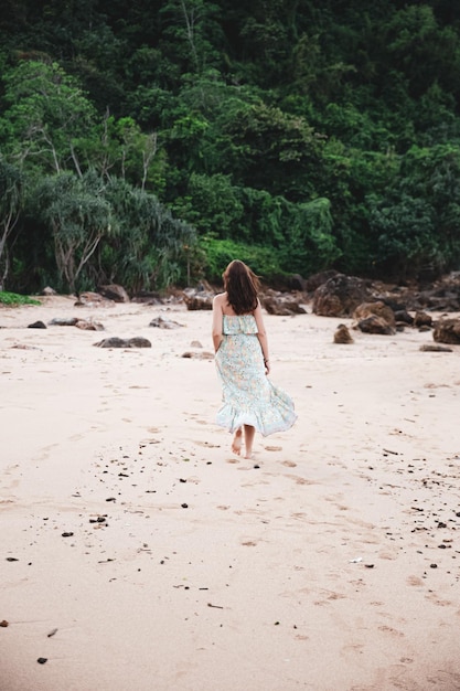 Jeune femme en robe marchant seule sur la plage dans la nature tropicale. Temps de repos