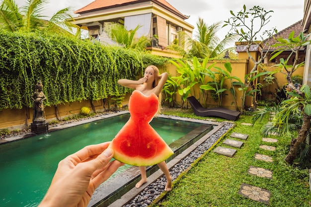 Jeune femme en robe pastèque sur fond de piscine Le concept de régime d'été et d'alimentation saine