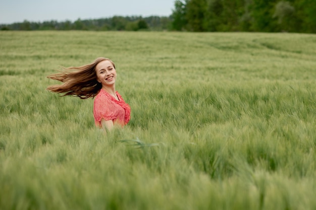 Jeune Femme En Robe Rouge Et Chapeau Marchant Dans Un Champ Vert D'orge Dans La Campagne Fille élégante En Robe Rustique Profitant D'un Moment Paisible Dans L'herbe En été Moment Rural Tranquille Espace De Copie