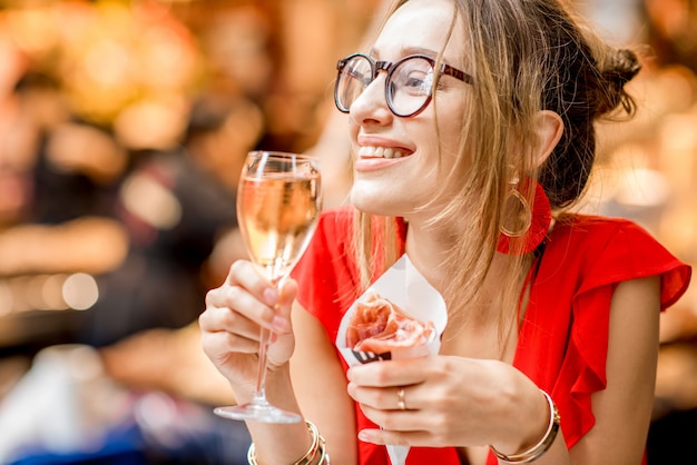 Jeune femme en robe rouge mangeant du jambon espagnol traditionnel jambon sec avec verre de vin assis au marché alimentaire de Barcelone