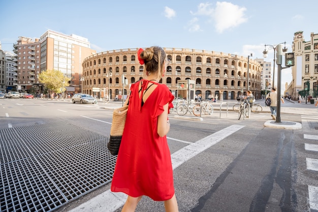 Jeune femme en robe rouge marchant dans la rue près de l'amphithéâtre des arènes de la ville de Valence, Espagne