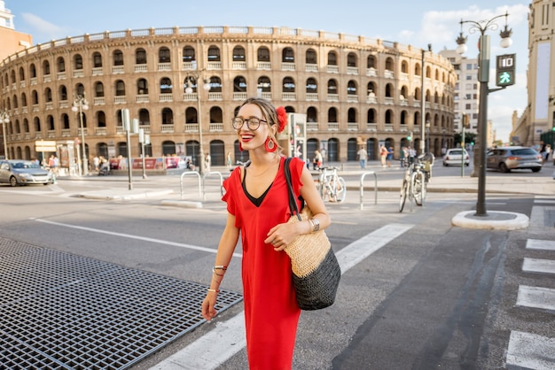 Jeune femme en robe rouge marchant dans la rue près de l'amphithéâtre des arènes de la ville de Valence, Espagne