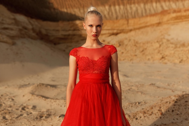 Jeune femme en robe rouge regardant la caméra sur le fond de la carrière des sables.