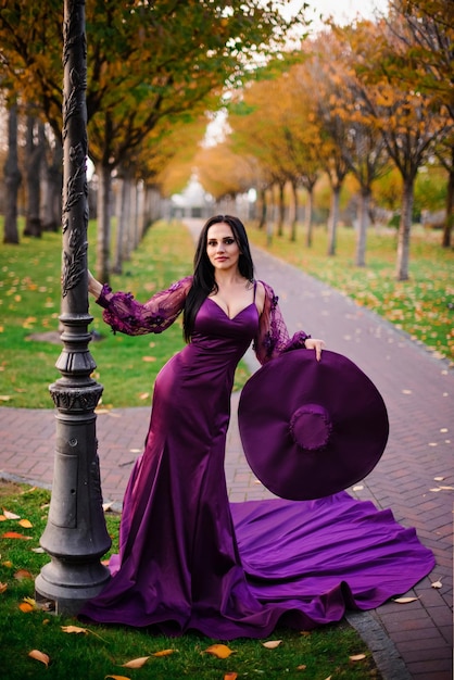 Jeune femme en robe de soie vintage est debout dans le parc de l'automne