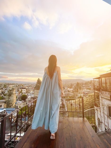 Jeune femme en robe sur le toit avec vue imprenable sur la Cappadoce en Turquie