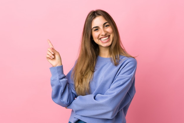 Jeune femme sur rose isolé heureux et pointant vers le haut