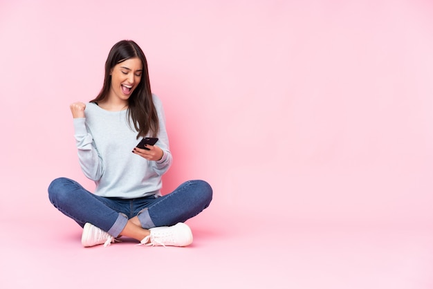 Jeune femme rose avec téléphone en position de victoire