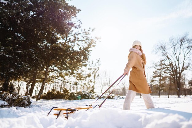 Jeune femme roule sur un traîneau dans la forêt enneigée d'hiver Nature vacances repos concept de voyage