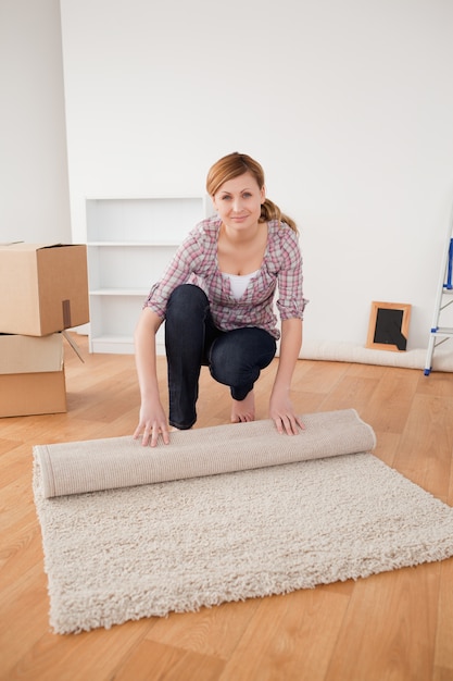 Jeune femme rouler un tapis pour se préparer à déménager