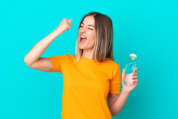 Jeune femme roumaine avec une bouteille d'eau isolée sur fond bleu célébrant une victoire