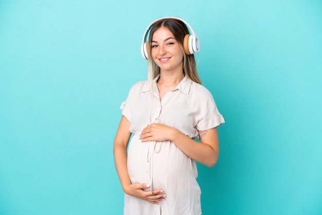 Jeune femme roumaine isolée sur fond bleu enceinte et écoutant de la musique