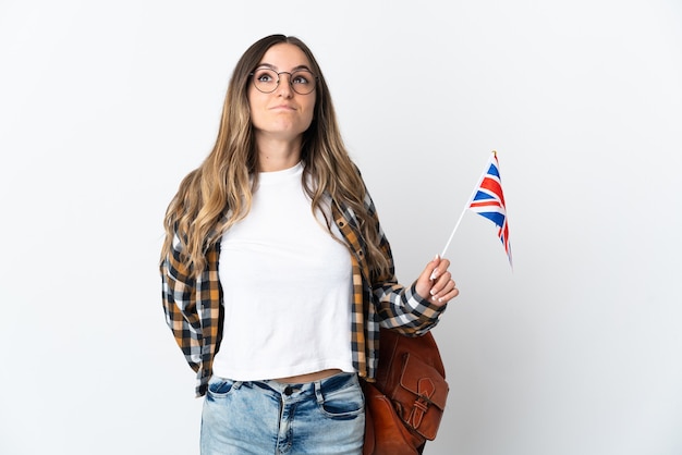 Jeune femme roumaine tenant un drapeau du Royaume-Uni isolé sur un mur blanc et jusqu'à