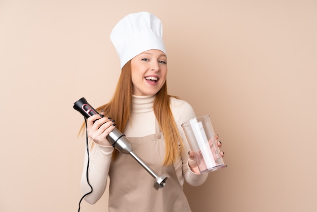 Jeune femme rousse à l'aide d'un mixeur plongeant