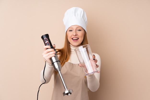 Jeune femme rousse à l'aide d'un mixeur plongeant