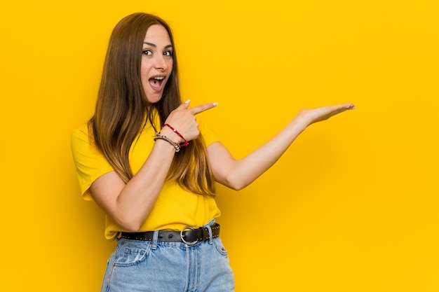 Jeune femme rousse au gingembre excitée tenant un espace de copie sur la paume.