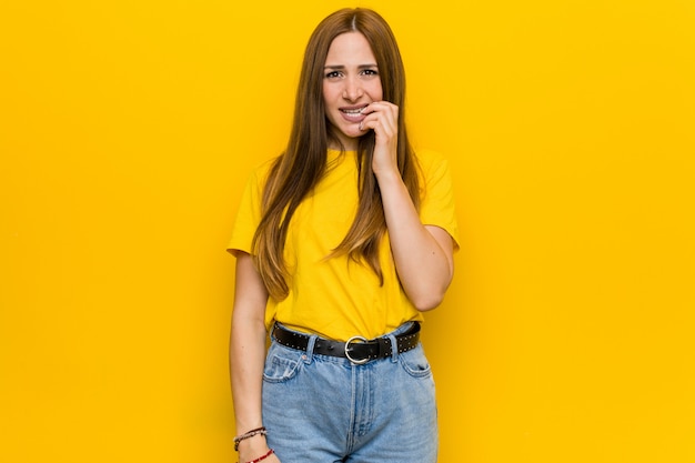 Jeune femme rousse au gingembre se rongeant les ongles, nerveuse et très inquiète.