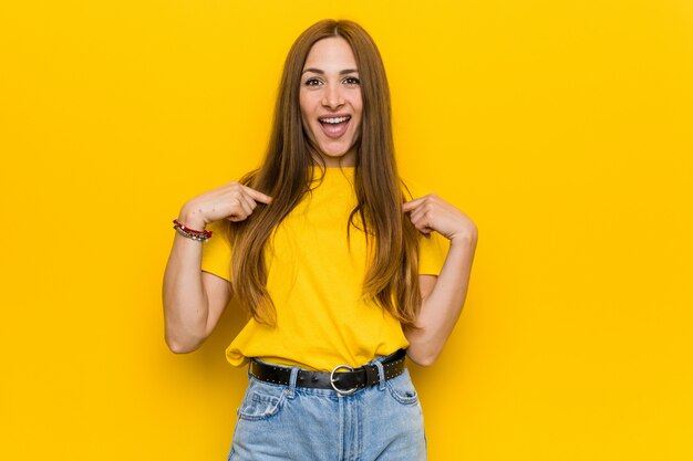 Jeune femme rousse au gingembre surpris pointant avec le doigt, souriant largement.