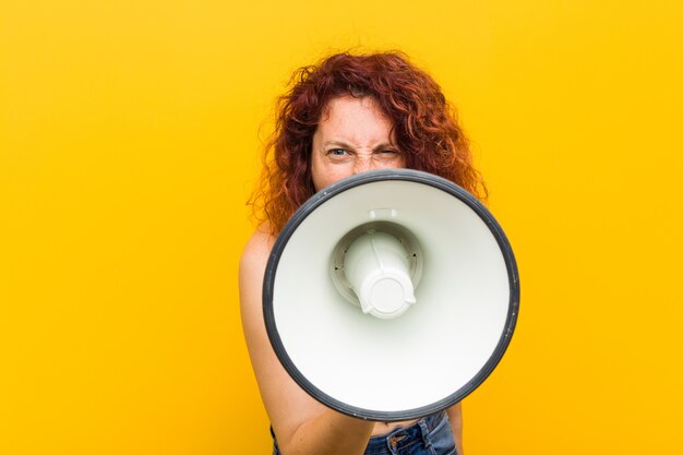 Jeune femme rousse caucasienne tenant un mégaphone