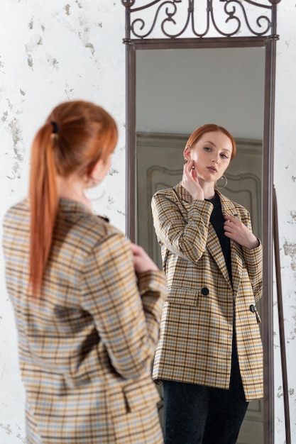 Photo jeune femme rousse devant un miroir pleine longueur