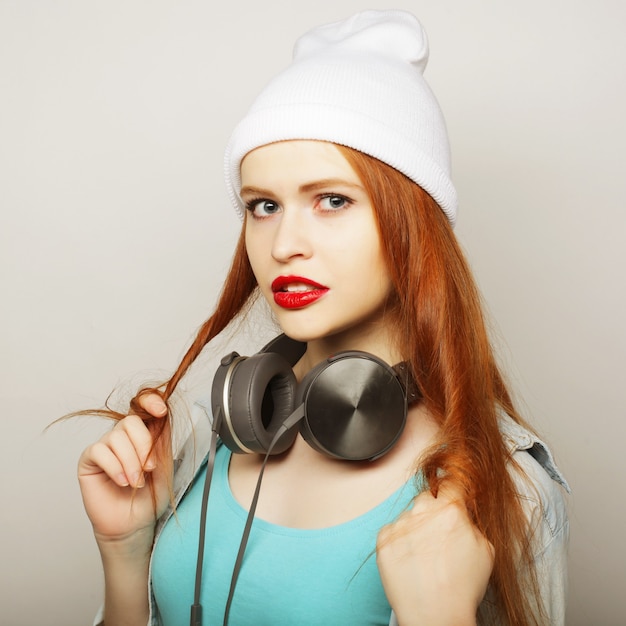 Jeune femme rousse avec des écouteurs écoutant de la musique.