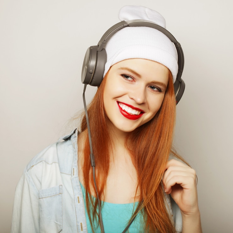 Photo jeune femme rousse avec des écouteurs écoutant de la musique.